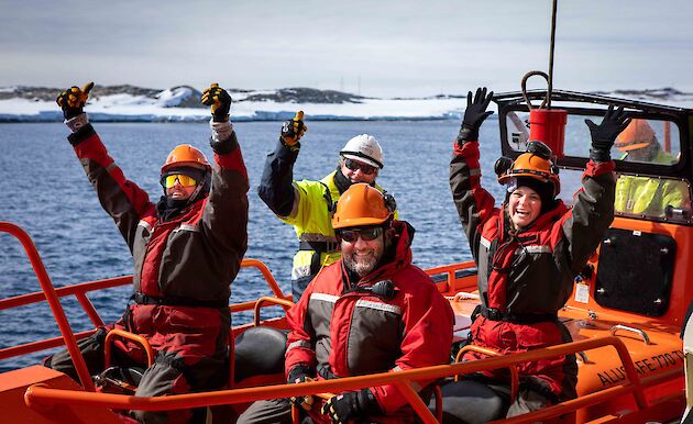 excited people in small boat lowered from ship