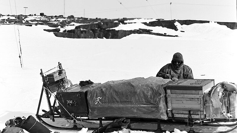 man with sledge in snow, black-and-white photo