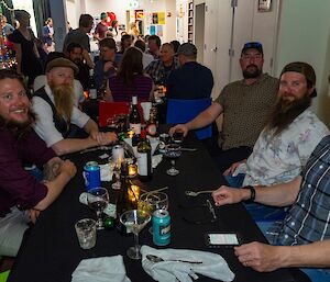 A close-up photo of a table of 5 people together at a dining table, enjoying drinks before dinner