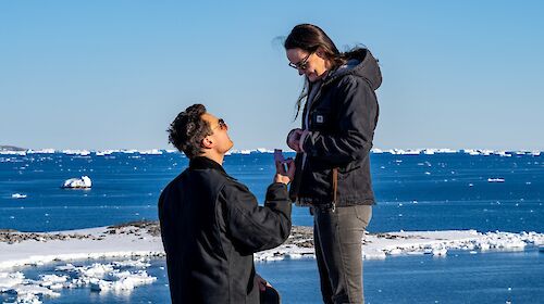 A man kneels down proposing to a woman