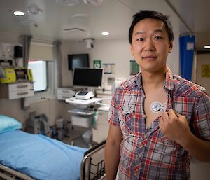 A man in a medical facility demonstrates a medical device on his chest