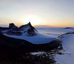 A stunning view of Fang Peak from Mt Elliot, with a winter sun in the background