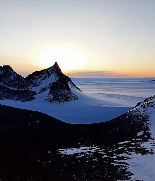 A stunning view of Fang Peak from Mt Elliot, with a winter sun in the background
