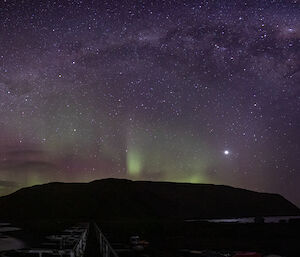 A green and purple aurora lights up over the island