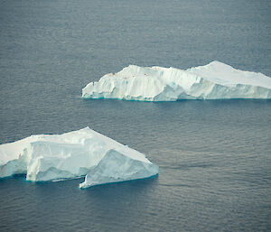 A zoomed-in view of two small icebergs in the ocean