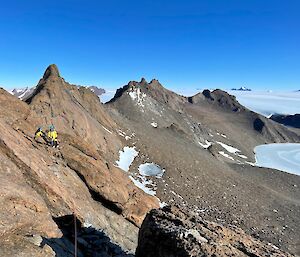 A spectacular view from Rumdoodle summit looking west, with expeditioners in the foreground nearly at the peak on a beautiful Mawson Day