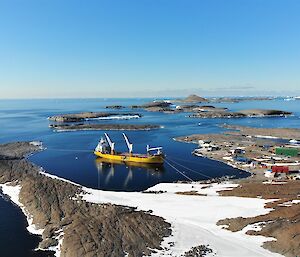 A cargo ship tied up in the habour next to the station under perfect clear skies