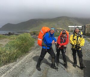 Three men with backpacks prepare themselves for a walk around the island