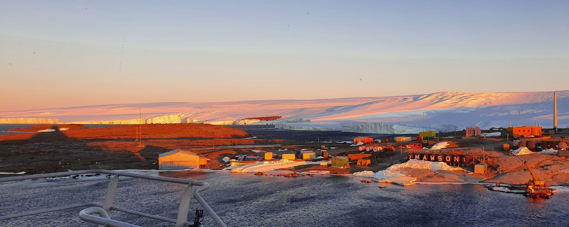 Sunset shot taken from a ship overlooking the station and surrounding snow and ice