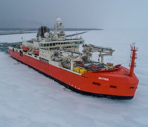 orange ship moving through ice covered sea