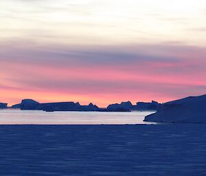 Sea ice, open ocean with silhouetted ice bergs against the sunset