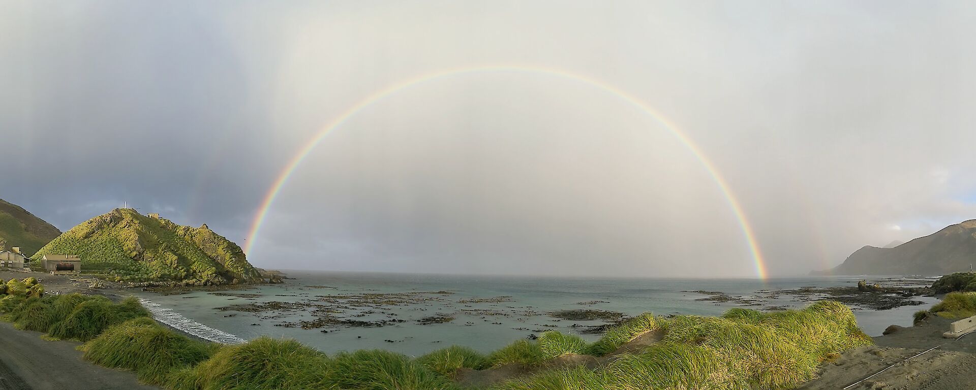 A rainbow across the water fills the space between two headlands
