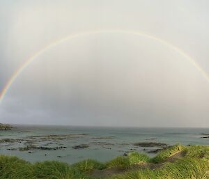 A rainbow across the water fills the space between two headlands