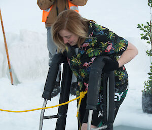 A woman descends into icy water cut from the sea ice