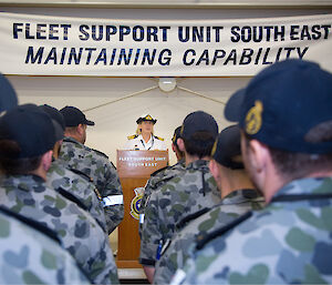 A woman addressed Navy personnel in uniform