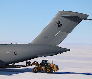 A hatch is opened in the rear of the C-17 plane. A heavy duty forklift vehicle has driven up to the open hatch to receive its cargo containers