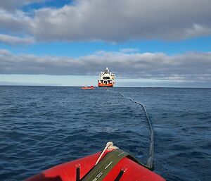 A hose carrying fuel inside floats on the ocean connected to an icebreaker