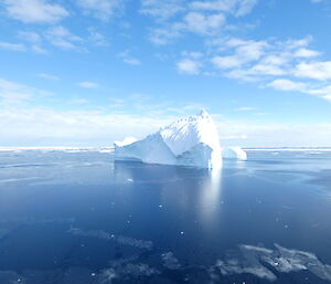 An iceberg floats by under a blue sky