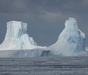 Two icebergs amongst the grey sky and sea