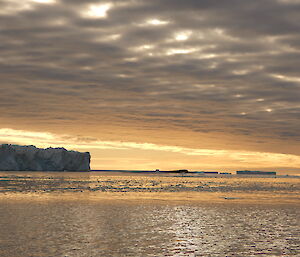 An iceberg and a golden sunset across the water