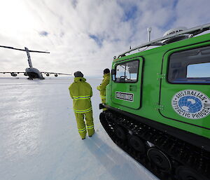 Two people in fire gear watch an aircraft unload