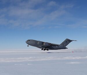 A grey plane takes off an ice runway in Antarctica