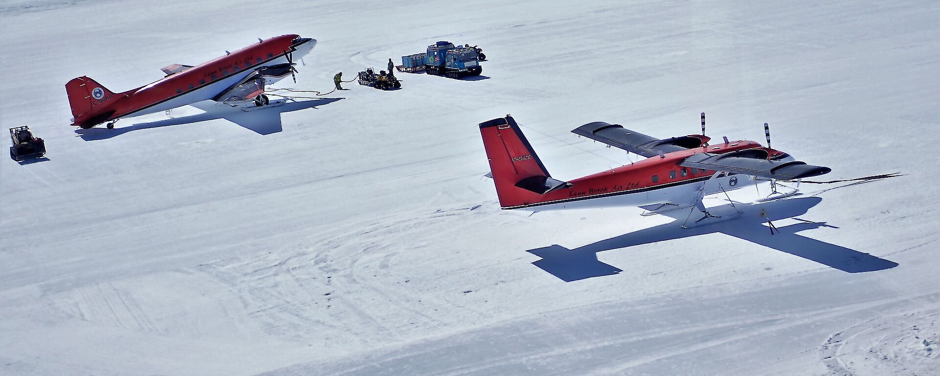 Two red planes parked on the ice