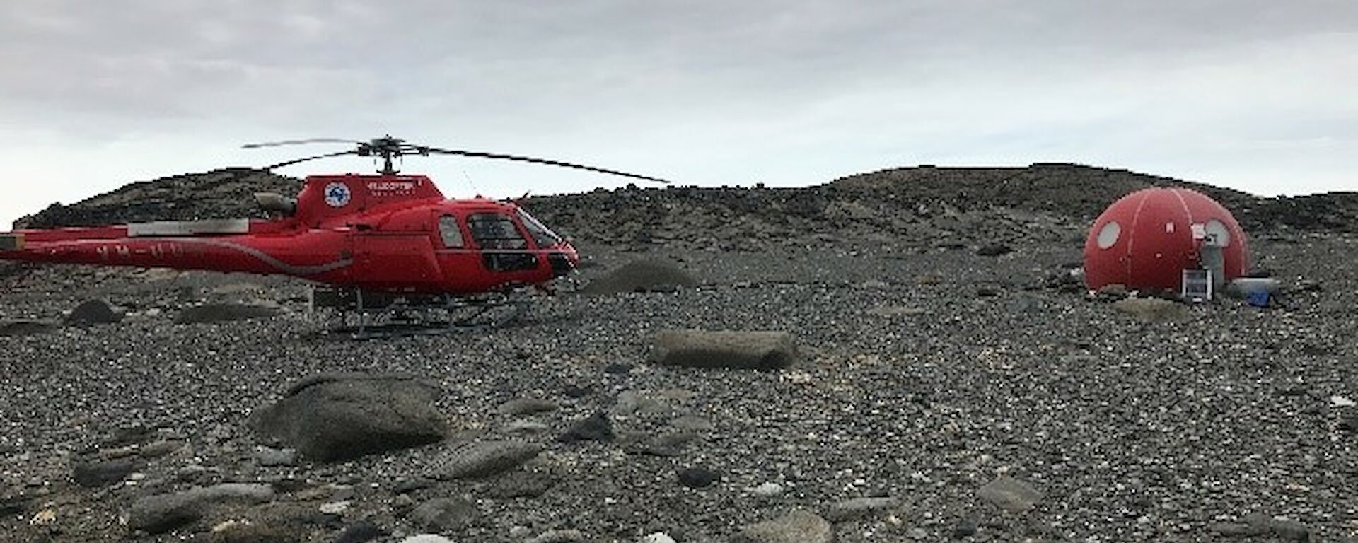 A helicopter and an apple shaped shelter on rocks