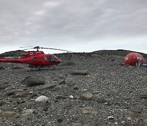 A helicopter and an apple shaped shelter on rocks