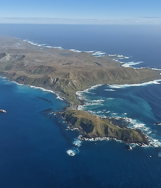 An aerial view of a red ship next to a mountainous island