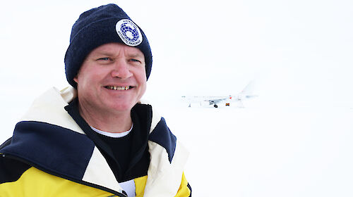 A man in a yellow jacket and beanie in Antarctica
