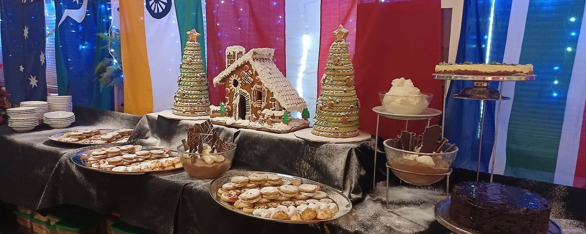 A table of Christmas desserts displayed on a table including a gingerbread house