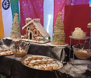 A table of Christmas desserts displayed on a table including a gingerbread house
