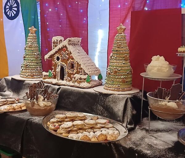 A table of Christmas desserts displayed on a table including a gingerbread house
