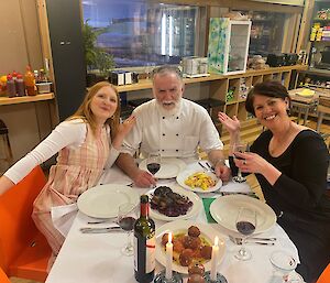 Three smiling people having dinner