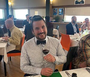 A man with a bow-tie smiles at the dinner table