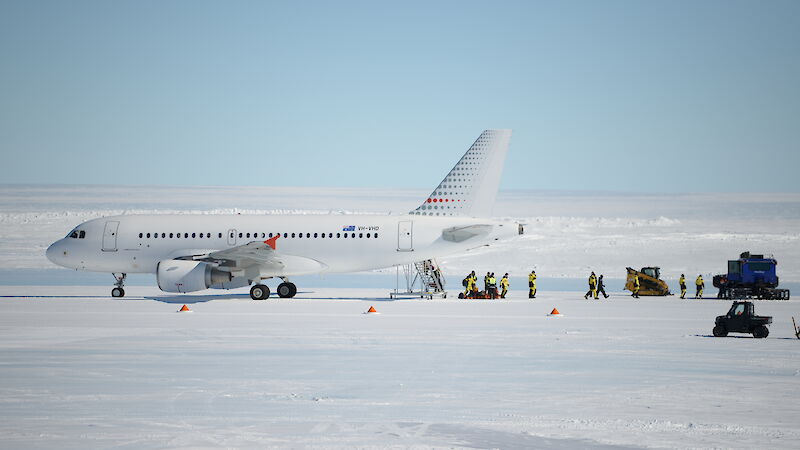 People walk away from a plane sitting on an ice runway