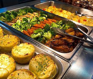 Bain-Marie filled with food; from left to right - potatoes, baked vegetables, roman gnocchi and lamb racks