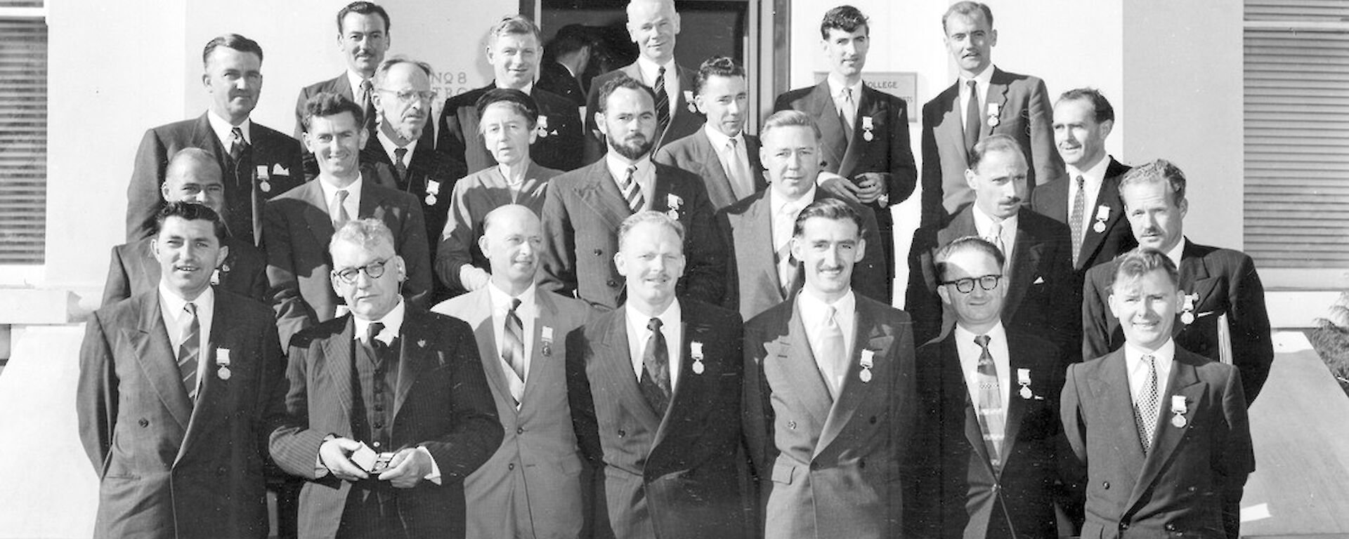 Group of suit wearing men pose on steps after medal presentation