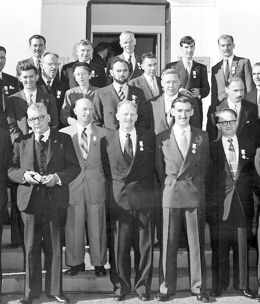 Group of suit wearing men pose on steps after medal presentation