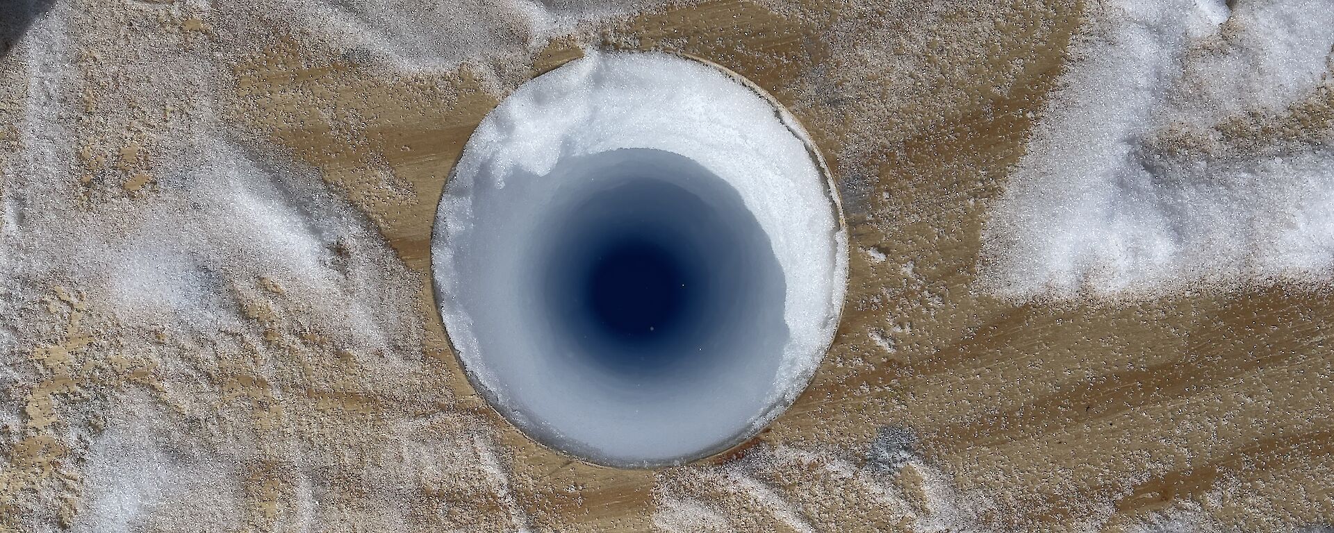 A hole in the ice with a wooden platform around it