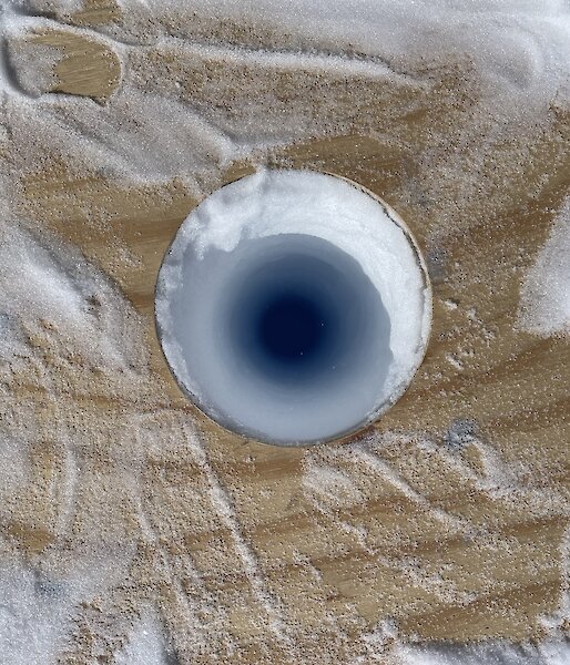 A hole in the ice with a wooden platform around it