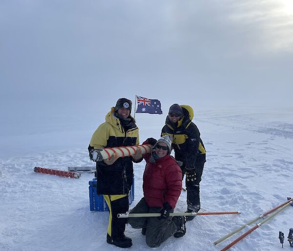 Three people hold a circular ice core