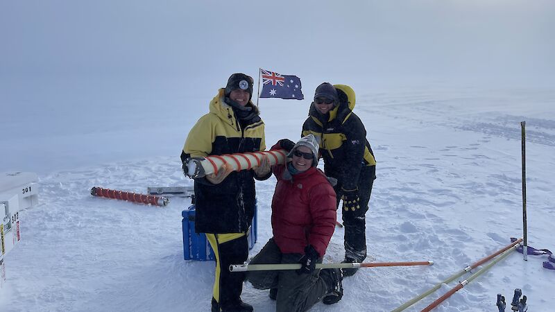 Three people hold a circular ice core