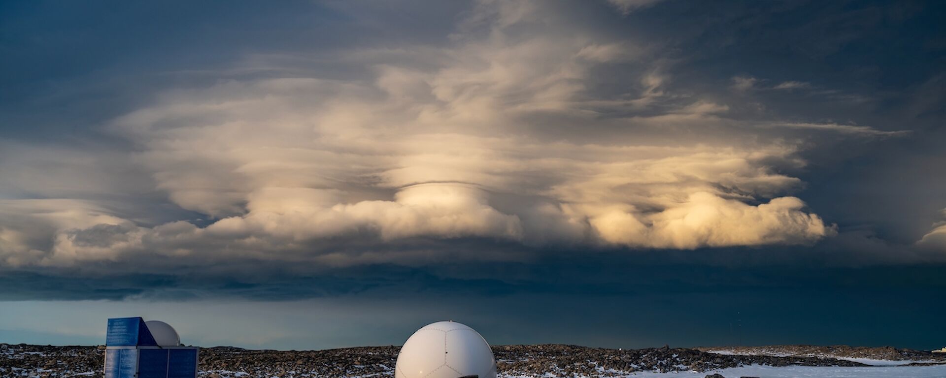 A towering cloud formation in the sky, appearing as flat layers rising from a fluffy base, widening out on top, with a nebulous column rising through the middle