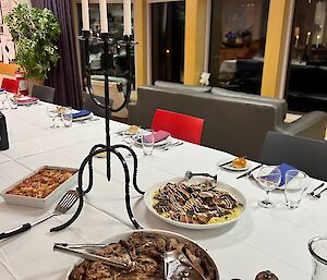 Dinner table set with cutlery, crockery, candelabra and platters of food