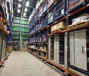 Lots of shelving in a store room holding boxes of food and supplies