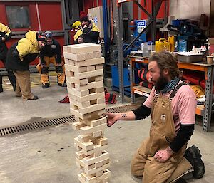 People playing a game called jenga, as an expeditioner pulls out a piece of wood from the game