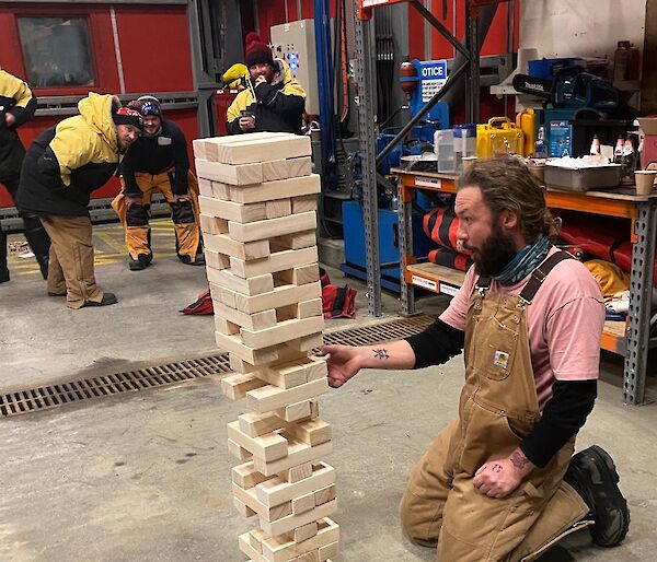 People playing a game called jenga, as an expeditioner pulls out a piece of wood from the game