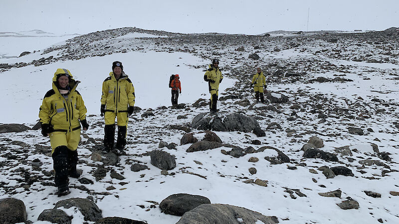 Five people standing on snow and rocks. The distance is completely white from the snow.